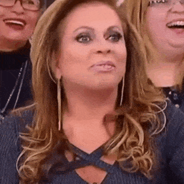 a woman is making a funny face while sitting in front of a crowd of people .