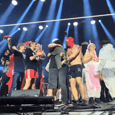 a group of people standing on a stage with one wearing shorts with the letter x on them