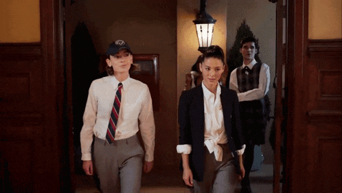 a group of people are walking down a hallway and one of them is wearing a hat with the letter r on it