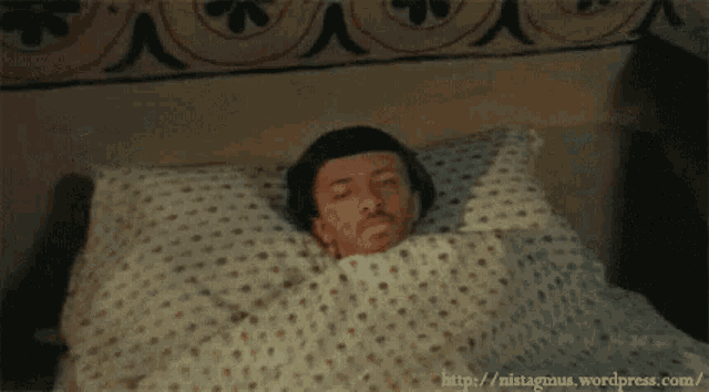 a man laying in a bed with a polka dot blanket