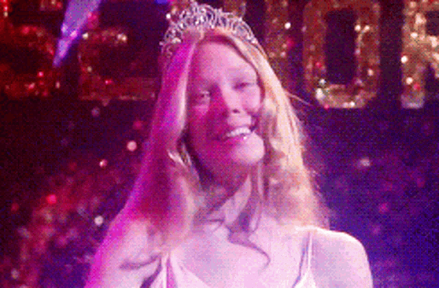 a woman wearing a tiara smiles in front of a sign that says 2000
