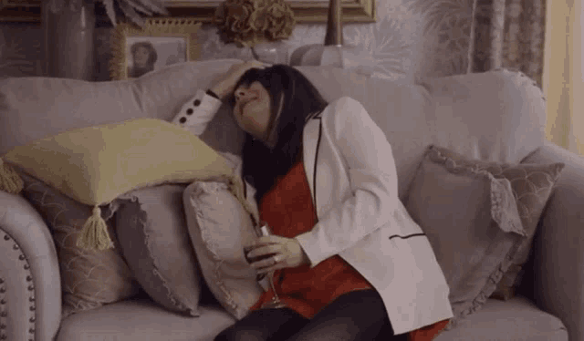 a woman sits on a couch with a glass of wine in her hand