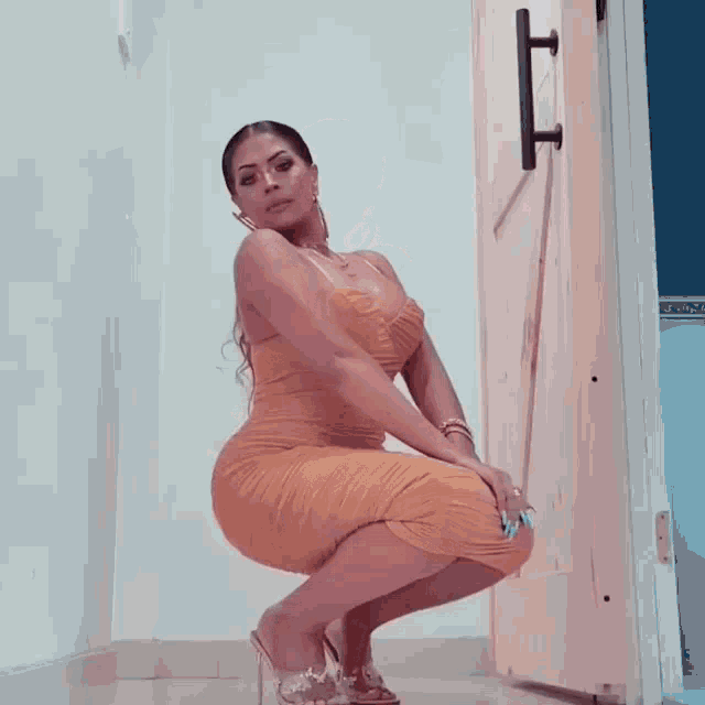 a woman in a yellow dress is squatting next to a door