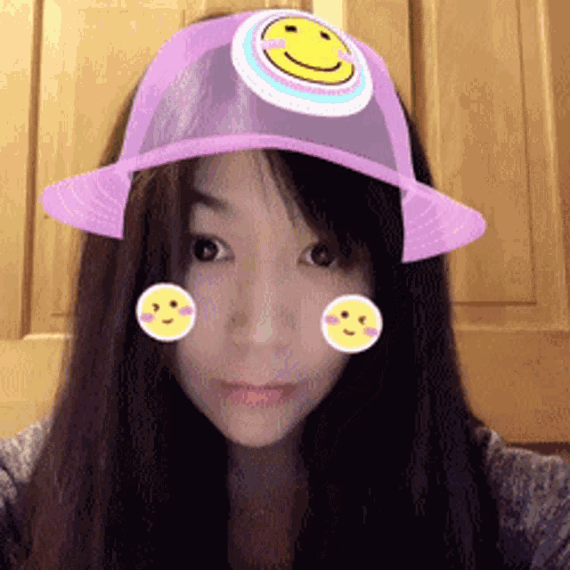 a woman wearing a pink hat with a smiley face on it