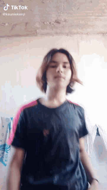 a young man wearing a black shirt and pink sleeves is dancing .