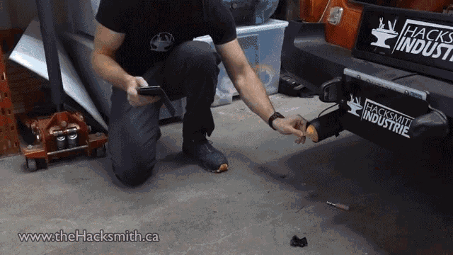 a man is kneeling down in front of a truck with a sticker on it that says hacksmith industrie
