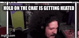a man is sitting in front of a microphone with the words `` hold on the chat is getting heated '' above him .