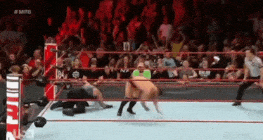a wrestling match is taking place in front of a crowd .