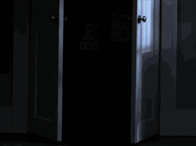 a door is open to a dark room with a light coming through it