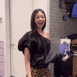 a woman in a black one shoulder top and leopard print skirt