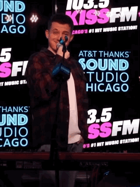 a man singing into a microphone in front of a sign that says at & t thanks sound studio chicago