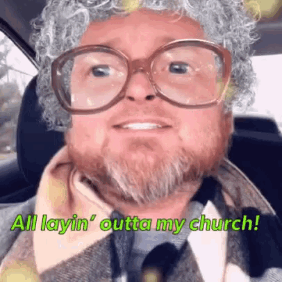 a man with glasses and a beard is sitting in a car and says " all laying outta my church "