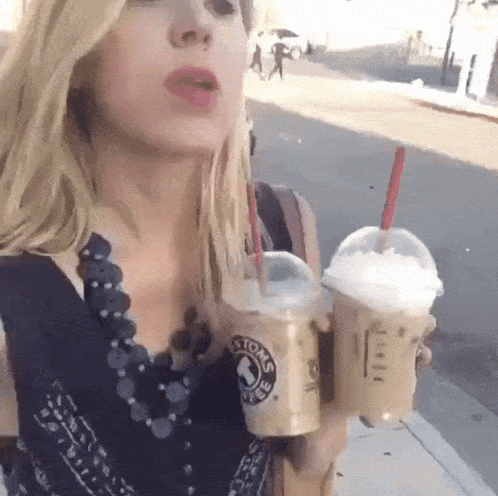 a woman is holding two cups of iced coffee with straws that say ' boston coffee ' on them