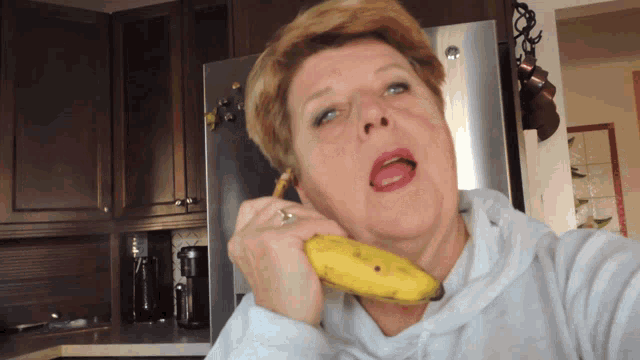 a woman is holding a banana in front of a fridge