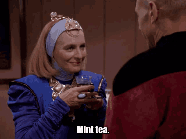 a woman in a blue dress holds a cup of mint tea