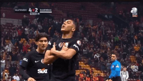 two soccer players are celebrating in front of a crowd and the scoreboard says galatasaray 4-2