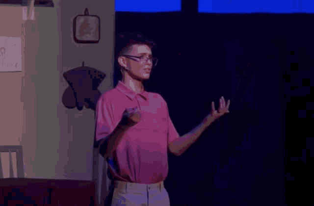a man in a pink shirt and glasses is standing on a stage
