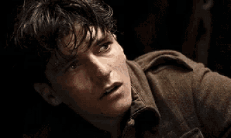 a close up of a man 's face in a dark room with a jacket on .