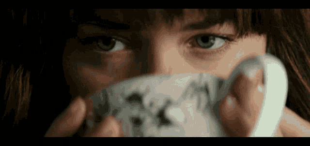 a close up of a woman covering her face with a cup of tea