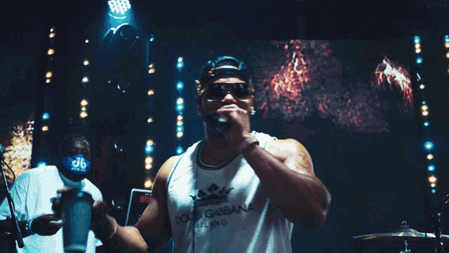 a man wearing sunglasses and a white tank top with the word adidas on the front