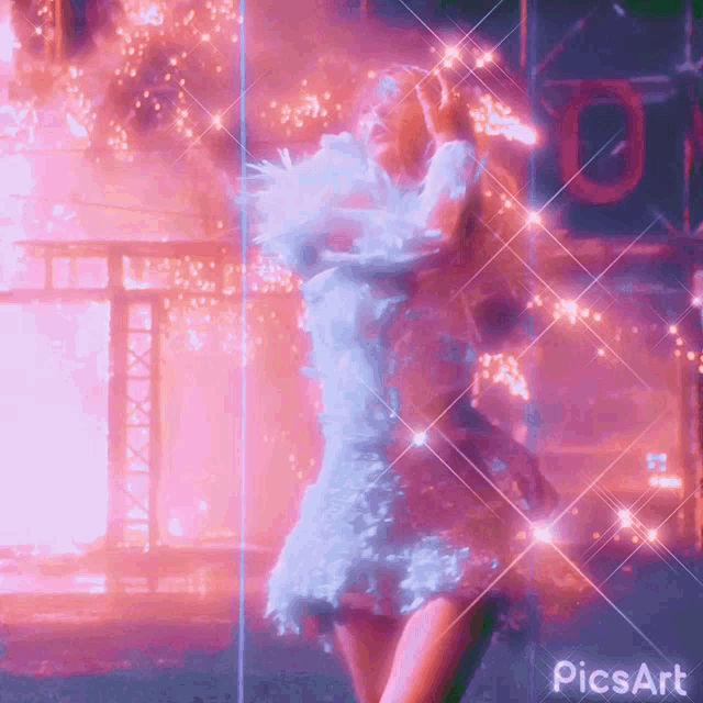 a woman in a blue dress is dancing in front of a fire and a sign that says picsart