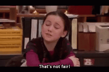 a young girl is sitting at a desk with her arms crossed and says `` that 's not fair ! ''
