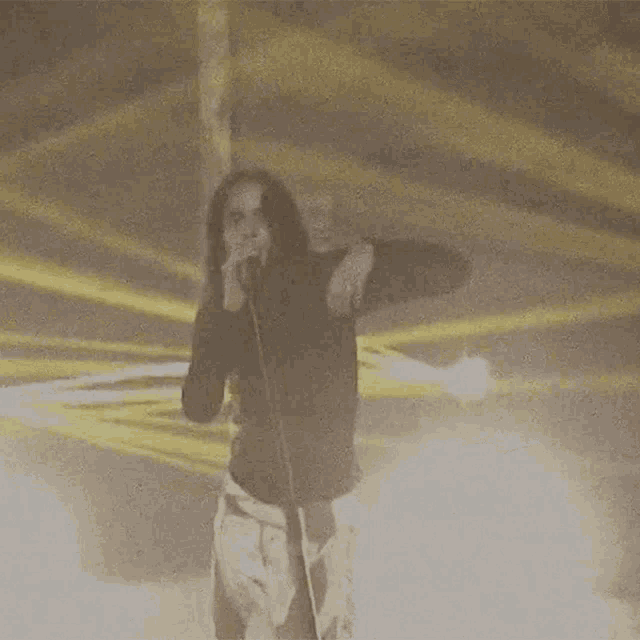 a woman is singing into a microphone while standing in front of a fire .