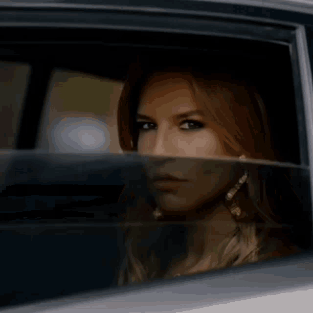 a woman is sitting in a car and looking out the window .
