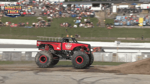 a monster truck is driving on a track with a crowd in the background