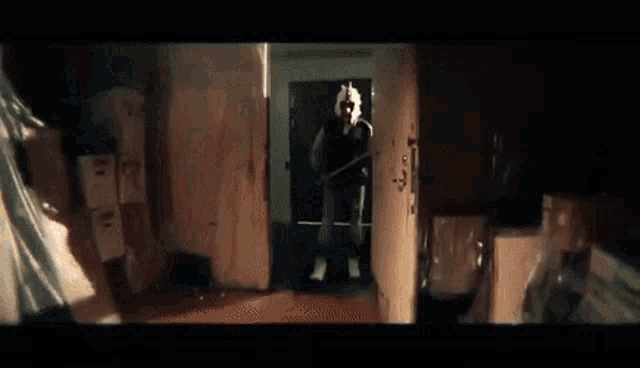 a man is holding a baseball bat and talking on a cell phone in a dark room .