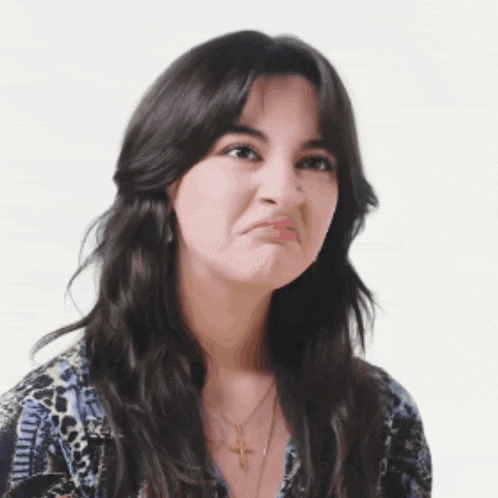 a woman wearing a necklace with a cross on it makes a funny face
