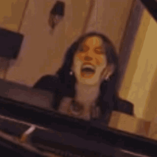 a woman is sitting on a stool playing a grand piano in a living room .