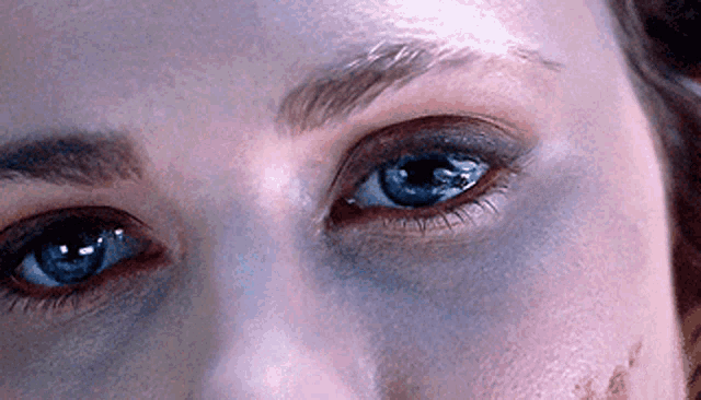 a close up of a woman 's blue eyes with a black spot on her face
