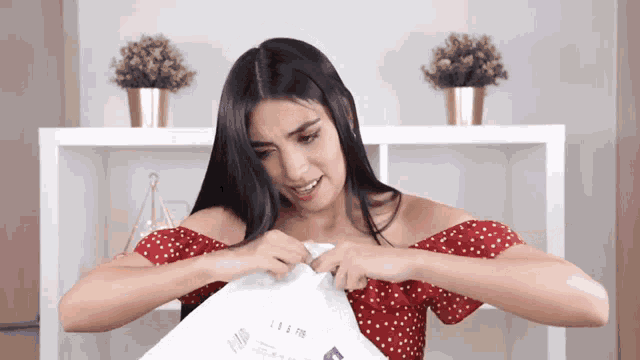 a woman in a red off the shoulder top is holding a piece of paper with the letters ii & ii on it