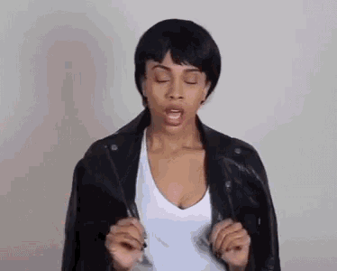 a woman wearing a black leather jacket and a white tank top is making a funny face .