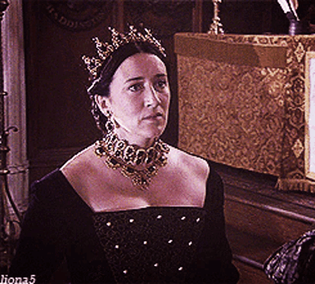 a woman wearing a crown and a necklace is standing in front of a sign that says ' lions 5 '