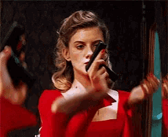 a woman in a red dress is holding two guns in her hand .