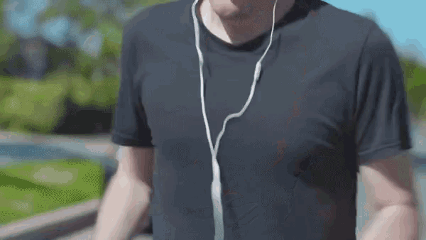 a man wearing headphones and a black shirt is walking down the street .
