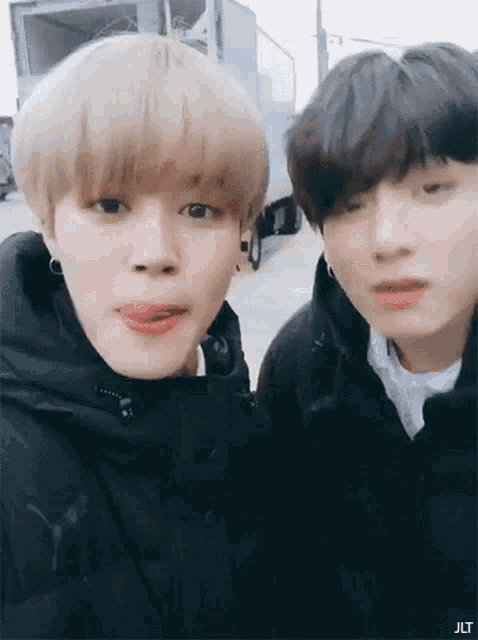 a couple of boys are standing next to each other and one of them is sticking out his tongue