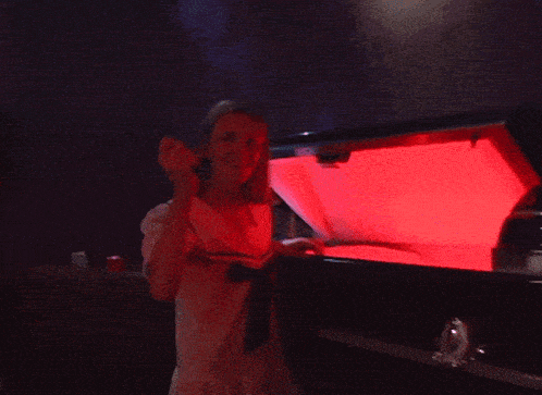 a woman in a white shirt is standing in front of a red light
