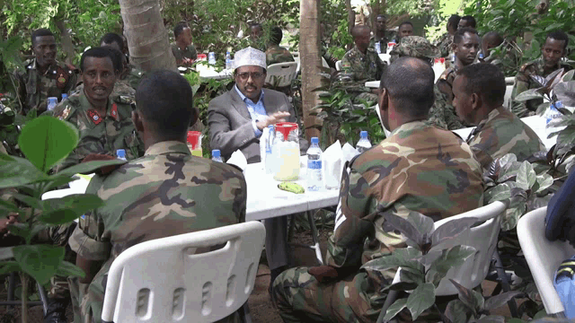 a group of soldiers sitting around a table with bottles of water on it