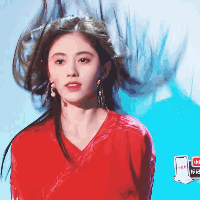 a woman in a red shirt has her hair blowing in the air