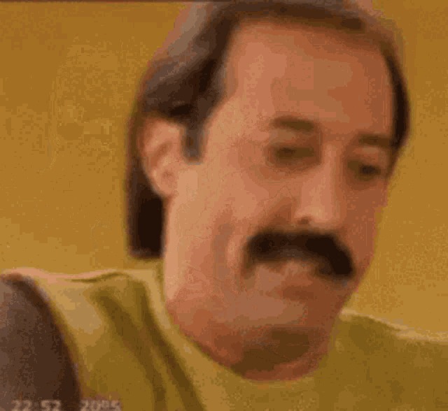 a man with a mustache is drinking coffee from a cup .