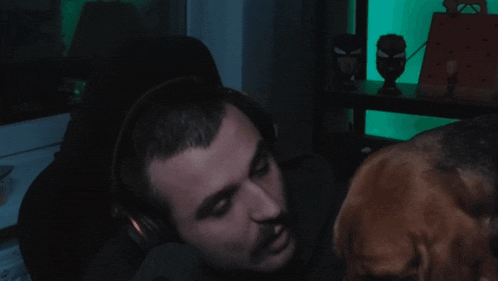 a man wearing headphones is being attacked by a dog who is looking at his face