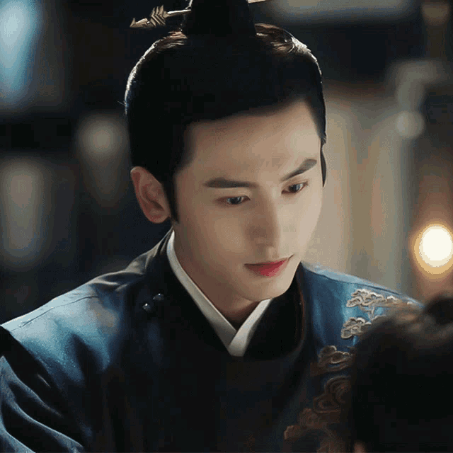 a man with a ponytail is wearing a blue robe