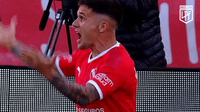 a soccer player wearing a red jersey that says seguros