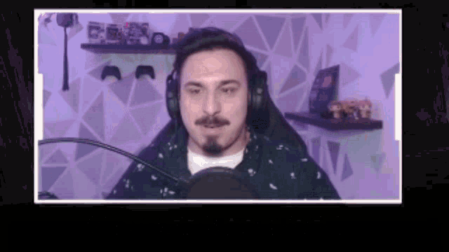 a man wearing headphones is sitting in front of a microphone in a room .