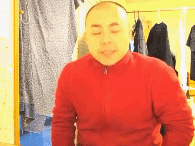 a man in a red jacket is standing in front of a shower curtain .