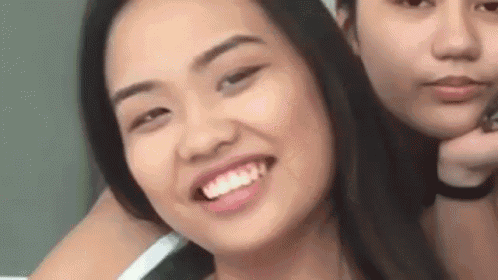 two young women are standing next to each other and smiling .