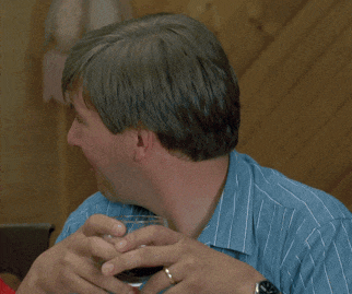 a man wearing a watch and a wedding ring holds a glass of wine